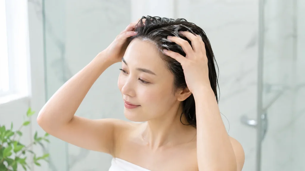 濡れた髪と頭皮にクリームシャンプーをなじませる女性